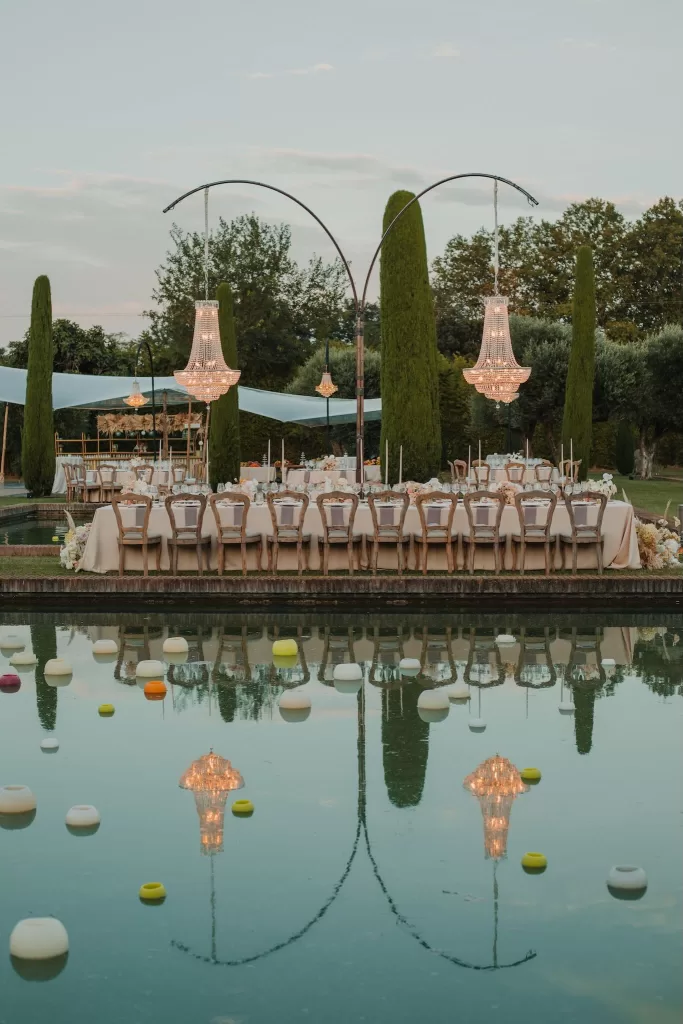 Long wedding table reflected in pools with chandeliers at Mas de Les Voltes.