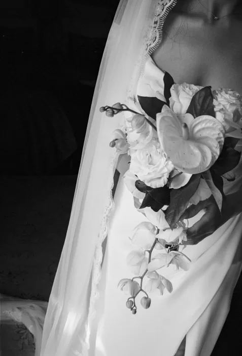 Black and white close-up of bride holding a cascading white floral bouquet at Masia Victoria.