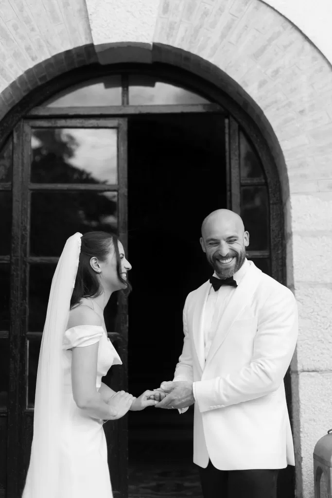 Black and white photo of bride and groom laughing together outside Masia Victoria.