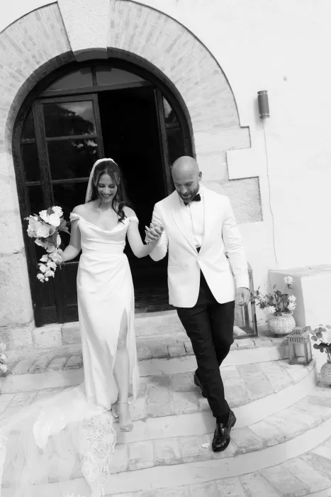 Black and white photo of the newlyweds walking hand in hand down the steps at Masia Victoria.