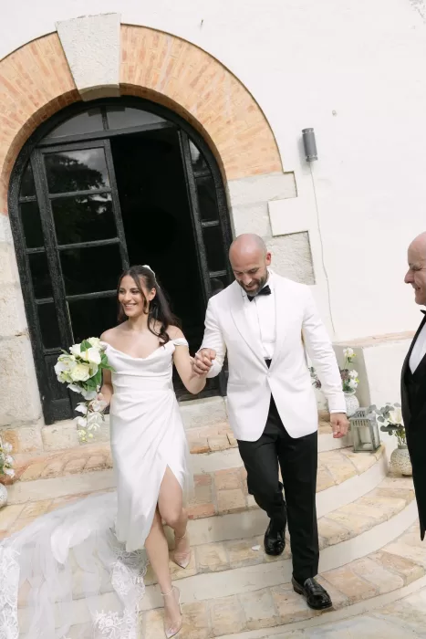 Bride and groom walking hand in hand, smiling after their ceremony at Masia Victoria.