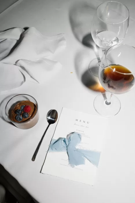 Elegant wedding menu with blue ribbon, dessert, and wine glass at Masia Victoria reception.