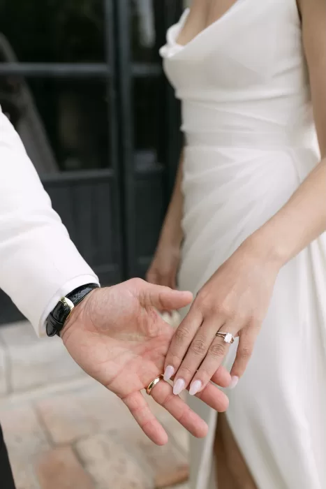Bride and groom showing their wedding rings in a romantic moment outside Masia Victoria.