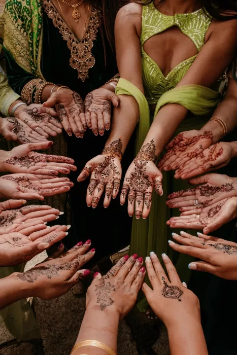 Group of women showing intricate mehndi designs on their hands during pre-wedding celebrations.