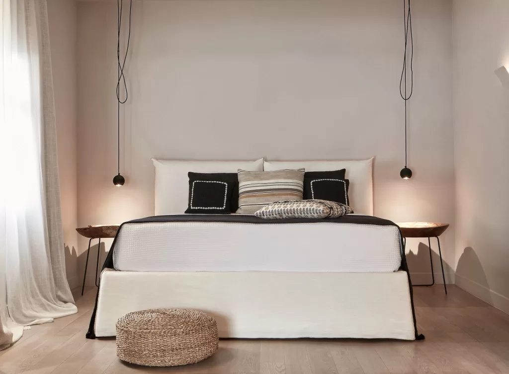 Calm neutral bedroom with black and striped cushions at Minos Beach Art Hotel.