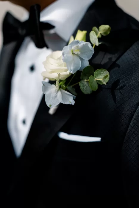 Groom’s black tuxedo with white and blue floral boutonniere at Minos Beach Art Hotel.