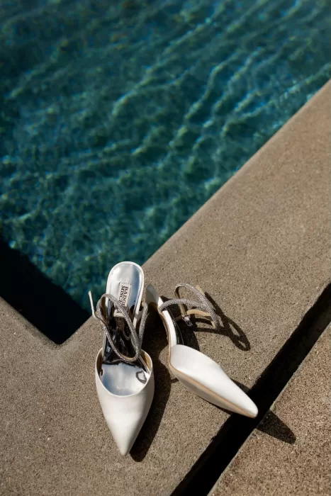 Black and white photo of bridal heels resting poolside at Minos Beach Art Hotel.