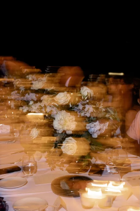 Artistic motion blur capturing candlelit wedding reception flowers and table setting at Minos Beach Art Hotel.