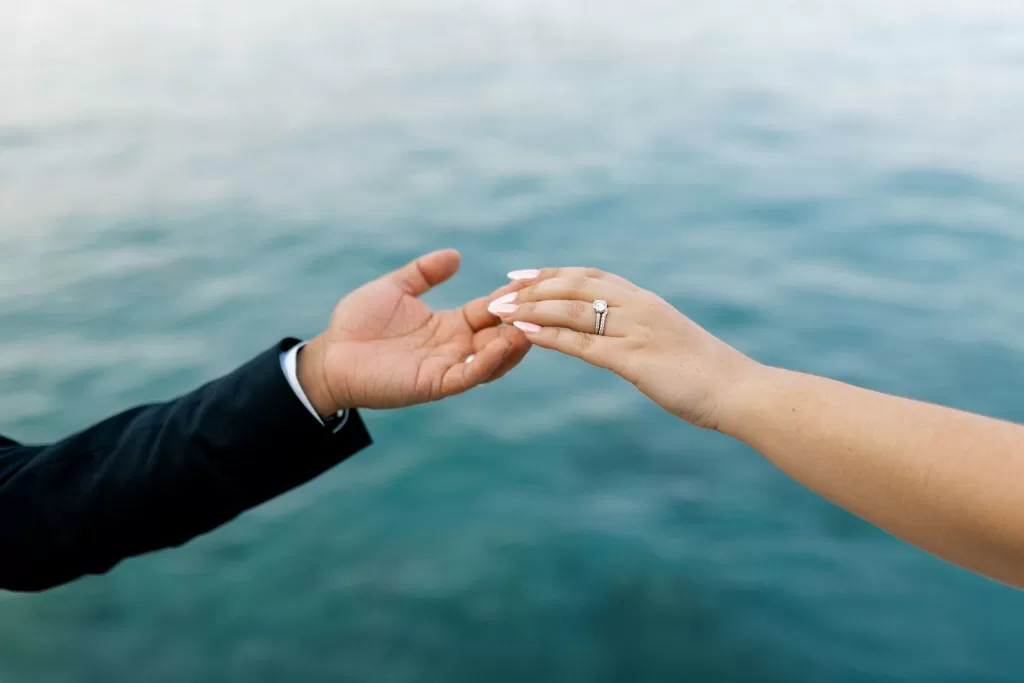 Bride and groom reaching hands towards each other over the blue waters at Minos Beach Art Hotel.