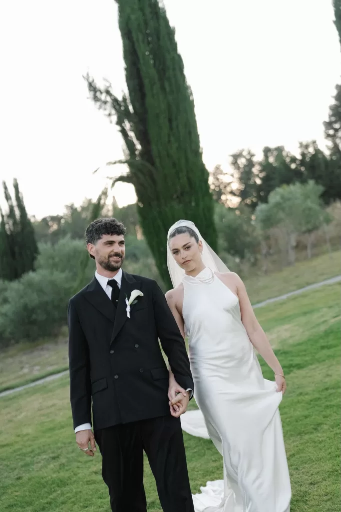 Bride and groom walking hand in hand across the lawn at Minthis Resort.
