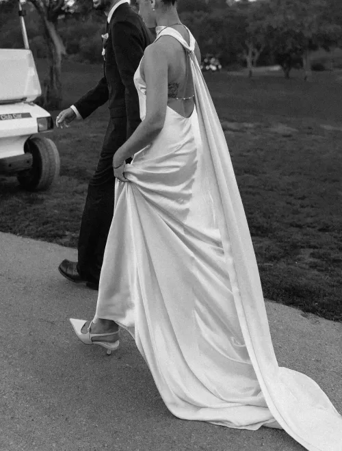 Black and white close-up of the bride’s flowing satin gown as she walks with the groom at Minthis Resort.