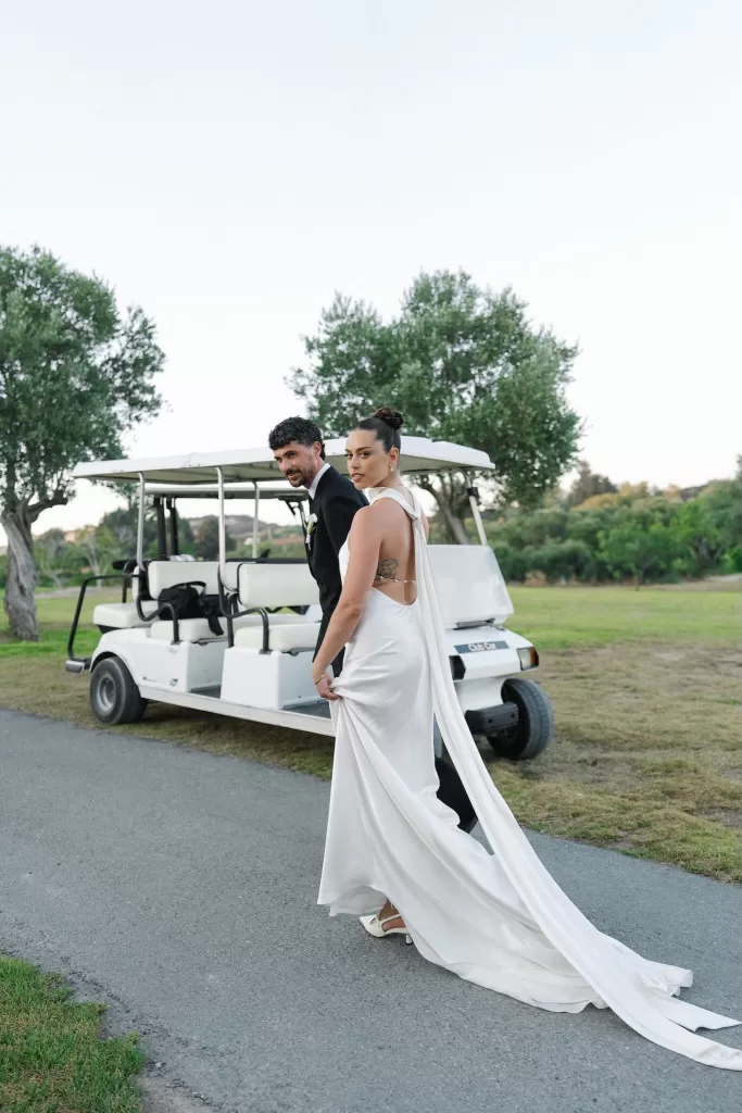 Bride and groom walking past a golf cart at Minthis Resort, the bride holding her long train.