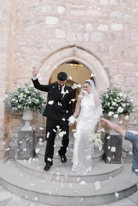 Newlyweds exiting the chapel at Minthis Resort under a shower of white petals.