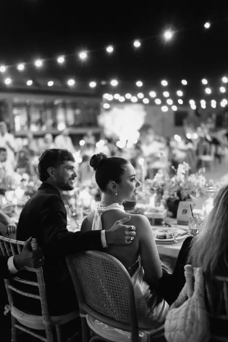Black and white image of bride and groom seated under romantic string lights at Minthis Resort reception.
