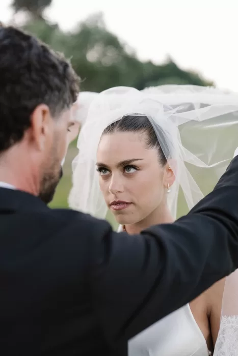 Groom lifting the bride’s veil as she gazes at him at Minthis Resort.
