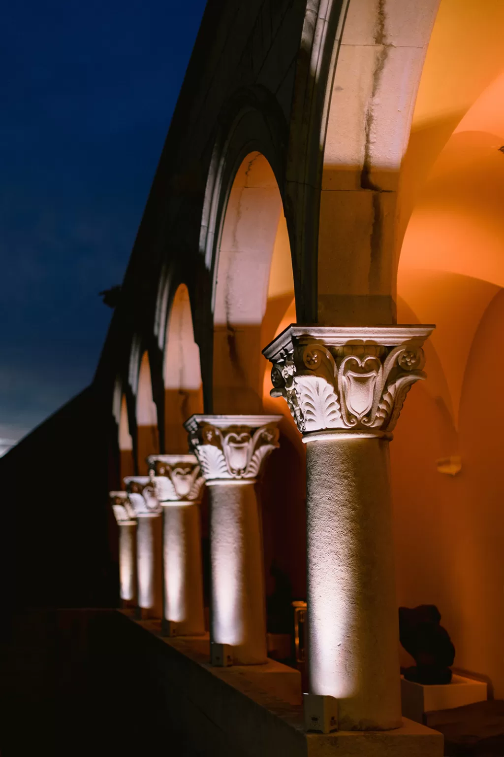 Dramatic stone arches of Museum of Modern Art Dubrovnik illuminated at night with warm golden light.