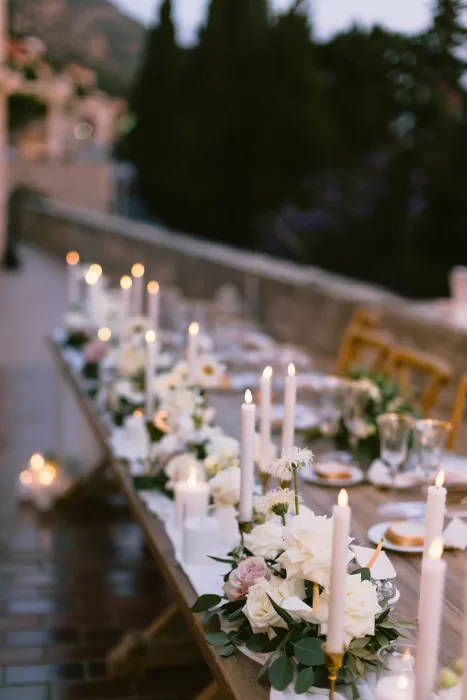 Long outdoor reception table at Museum of Modern Art Dubrovnik styled with white flowers, candles, and soft evening light.