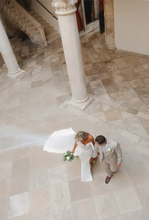 Bride and groom walking hand in hand across the stone courtyard at the Museum of Modern Art Dubrovnik.