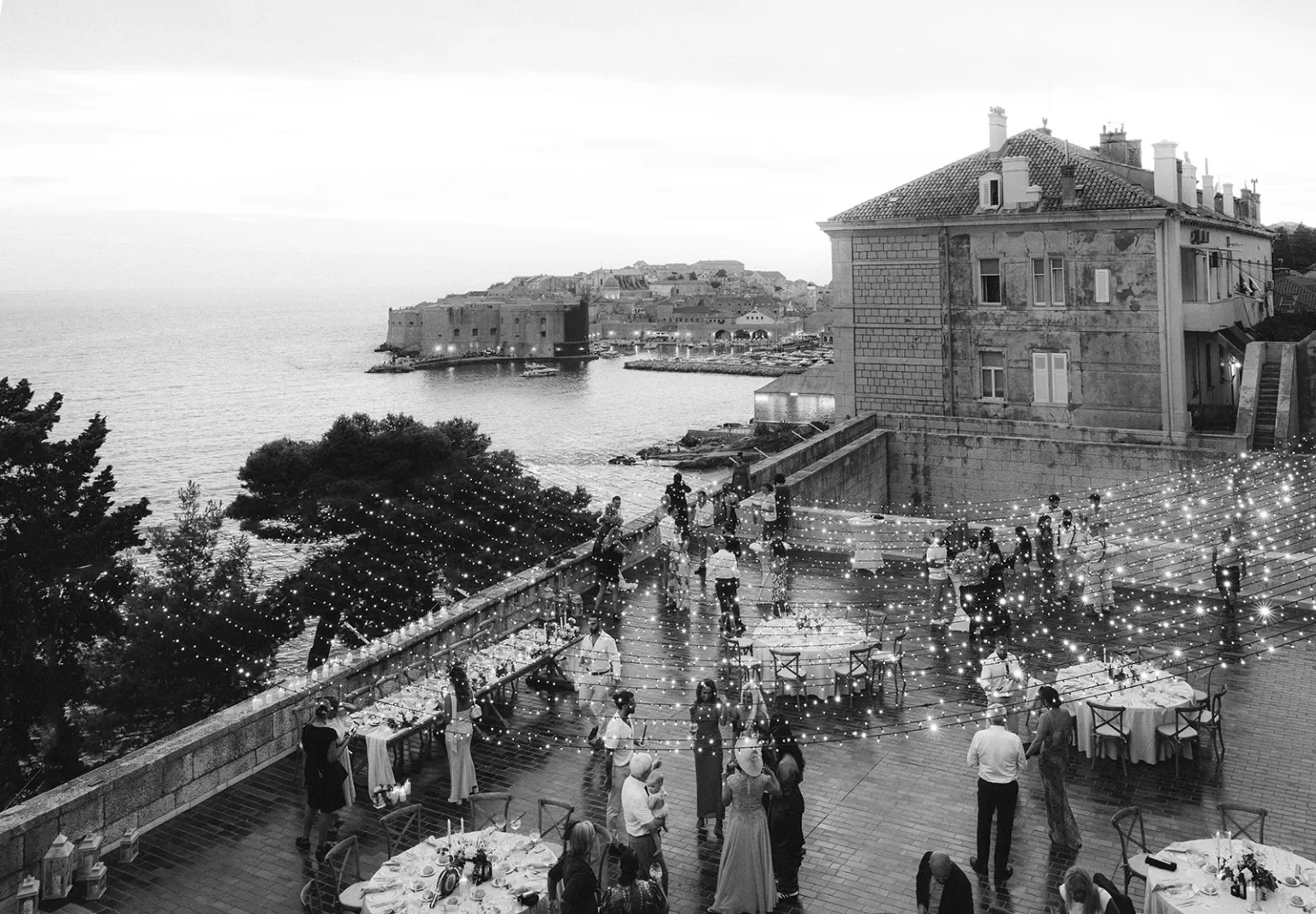 Guests dancing under string lights on the terrace at the Museum of Modern Art Dubrovnik with sea views.