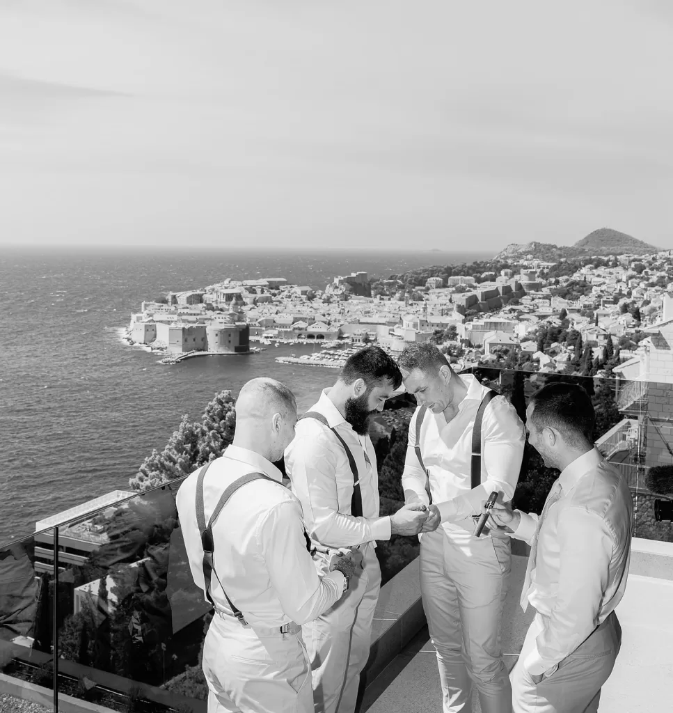 Groomsmen helping the groom get ready on a terrace overlooking Dubrovnik from the Museum of Modern Art.
