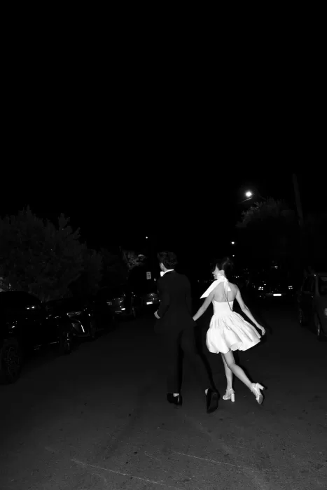 Bride and groom holding hands and walking down the street at night after their wedding reception.