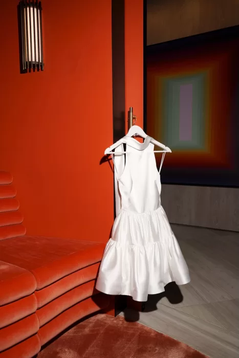 Short satin reception dress hanging against a bold red wall at Next Chapter Events.