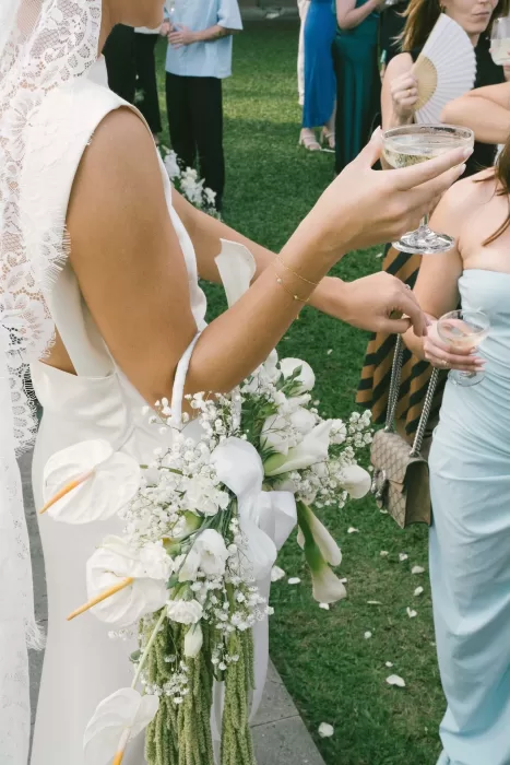 Bride holding a cascading bouquet of white flowers while celebrating at Padma Resort Legian.