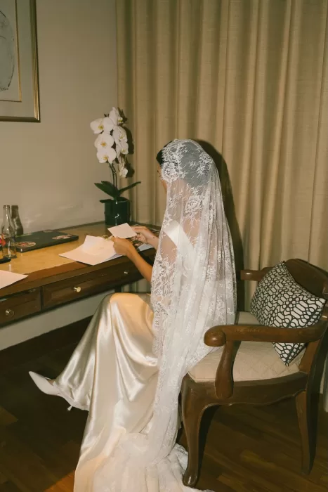 Bride in a lace veil reading a note before the ceremony at Padma Resort Legian.