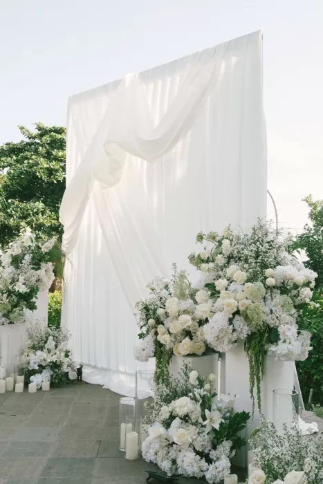 Elegant white draped altar with cascading floral arrangements at Padma Resort Legian.