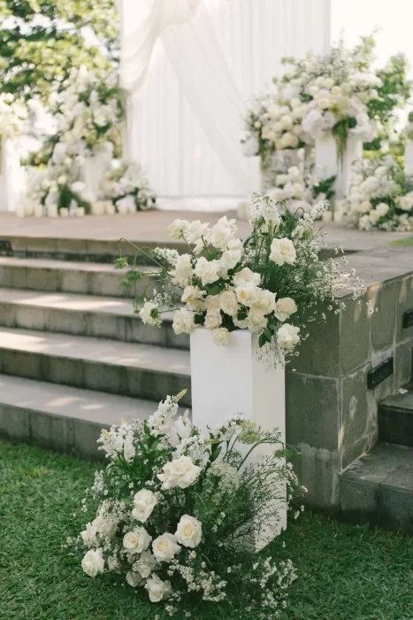 Romantic ceremony setup with white roses and greenery along the altar steps at Padma Resort Legian.