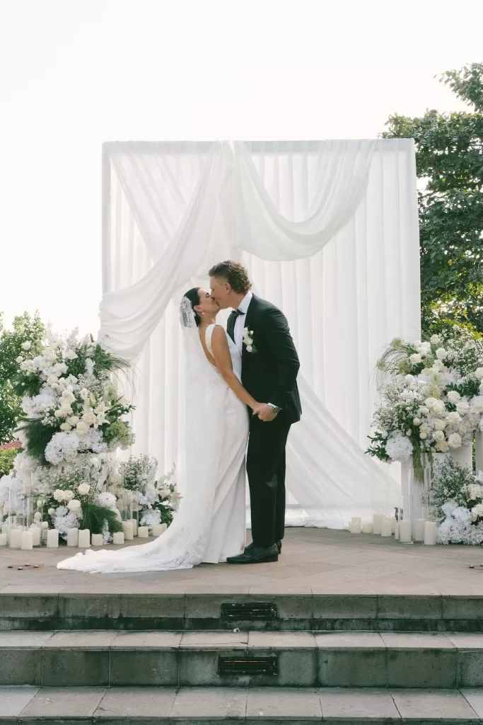 Bride and groom share their first kiss under a floral altar at Padma Resort Legian.