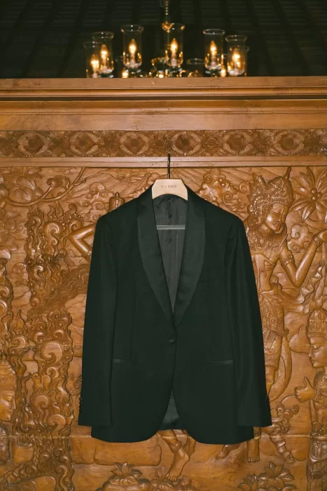 Groom’s black suit jacket on a wooden carved hanger at Padma Resort Legian.
