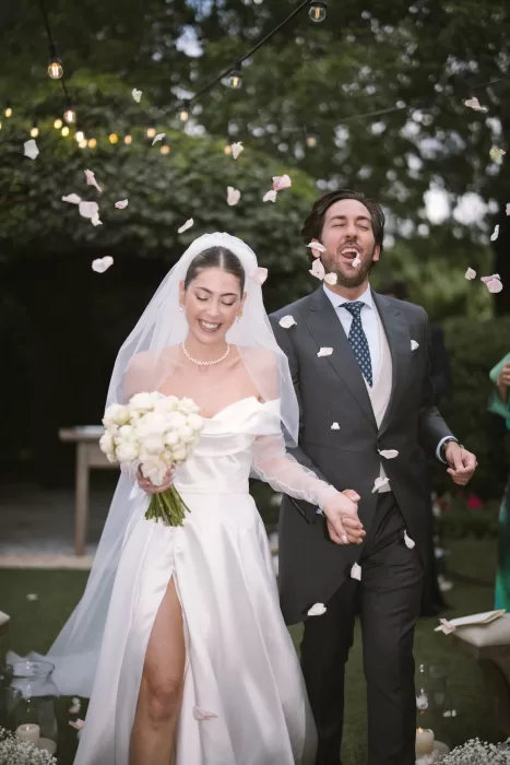 Just married couple exit under a shower of rose petals at Cigarral de la Mercedes, beaming with joy.