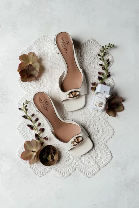 Flatlay of Valentino bridal shoes, wedding rings, and flowers styled at Rustico Bertel.