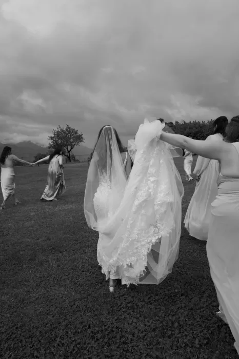 Bride with her bridesmaids walking across the grass in flowing gowns at Rustico Bertel.