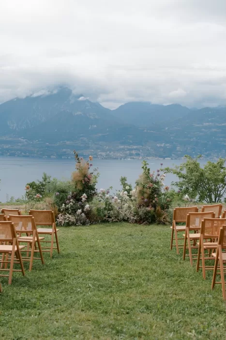 Outdoor ceremony setup with floral arch and wooden chairs overlooking Lake Garda at Rustico Bertel.