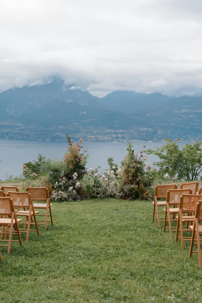 Outdoor ceremony setup with floral arch and wooden chairs overlooking Lake Garda at Rustico Bertel.
