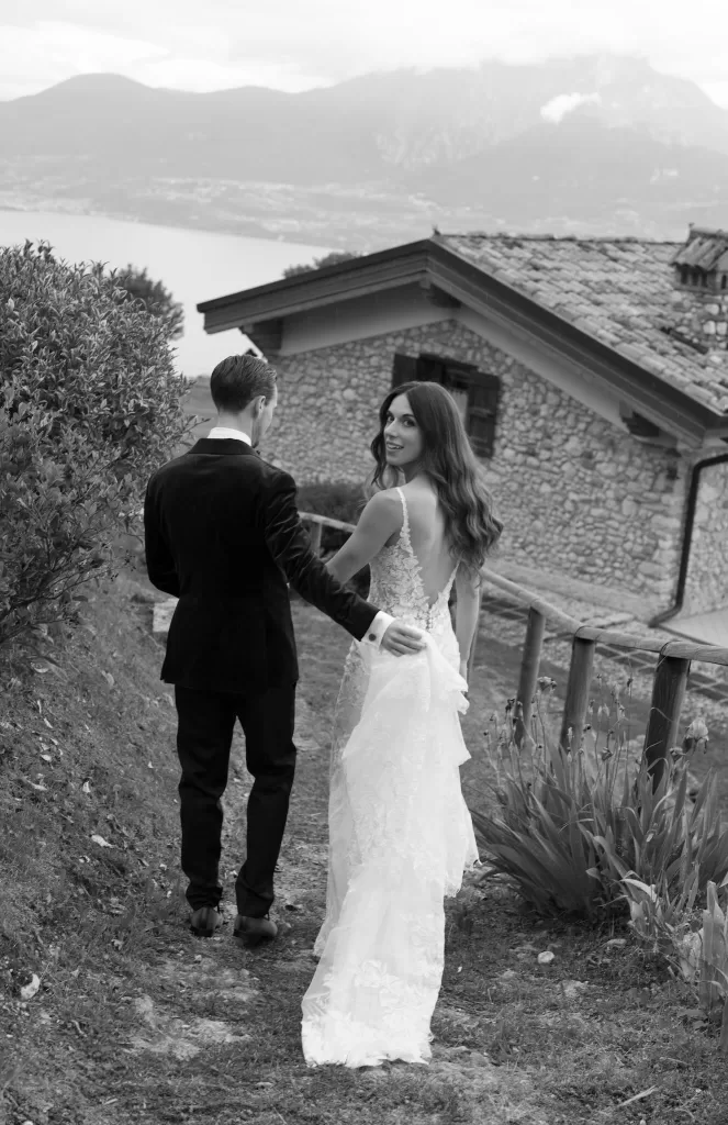 Bride looking back as she walks with the groom on a hillside path at Rustico Bertel.