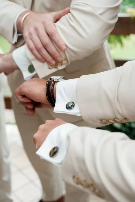 Groomsmen adjusting beige suits, showing cufflinks before the wedding at Rustico Bertel.
