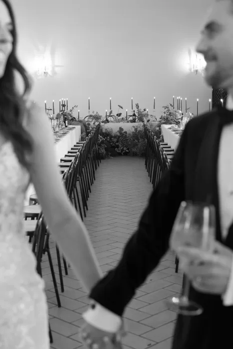 Wedding reception tables lined with candles and flowers in the grand hall of Rustico Bertel.