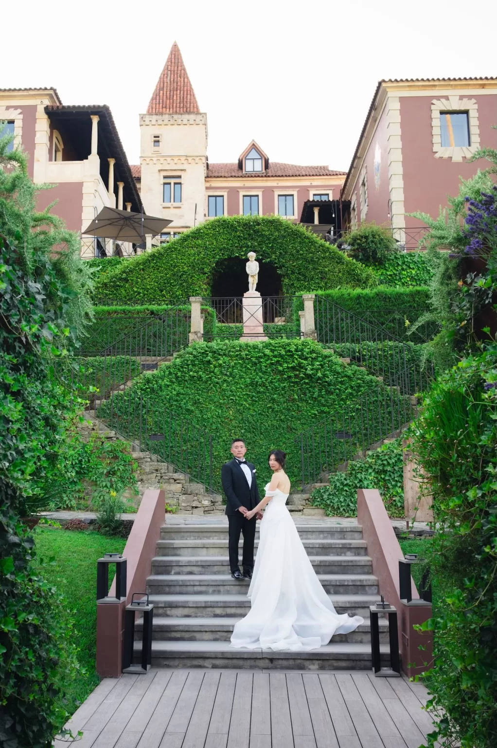 Bride and groom standing on stone steps with ivy-covered walls and a historic façade at Six Senses Douro Valley.