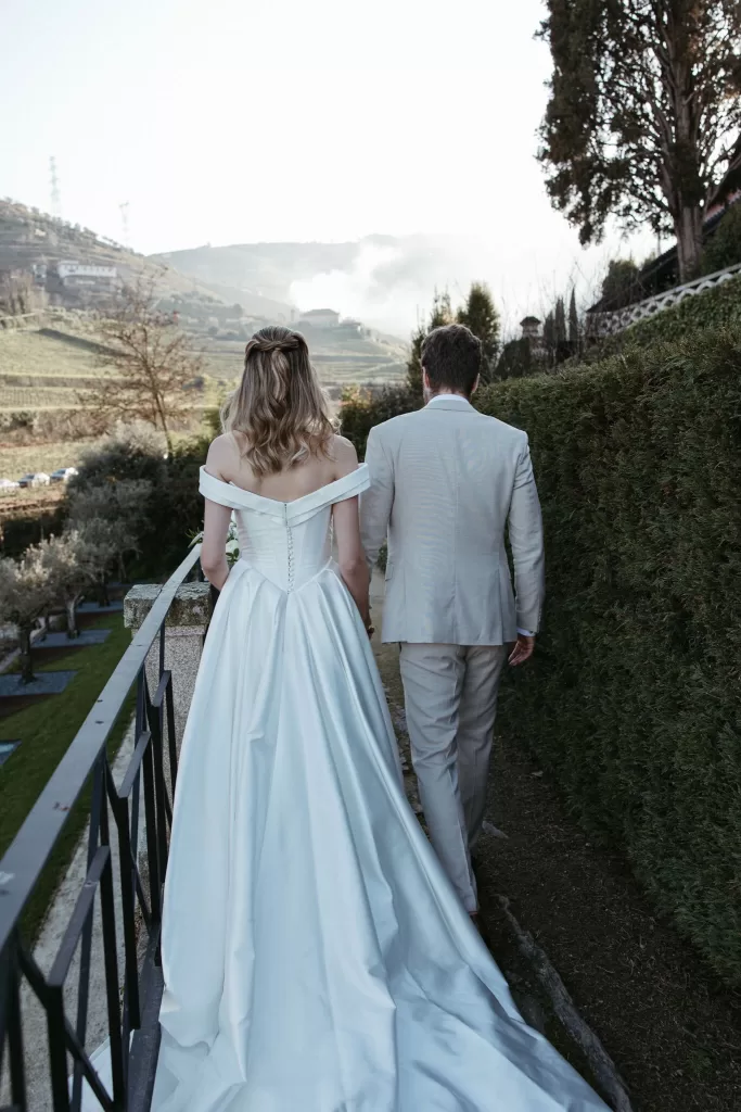 Bride and groom walking together overlooking vineyard hills at Six Senses Douro Valley.