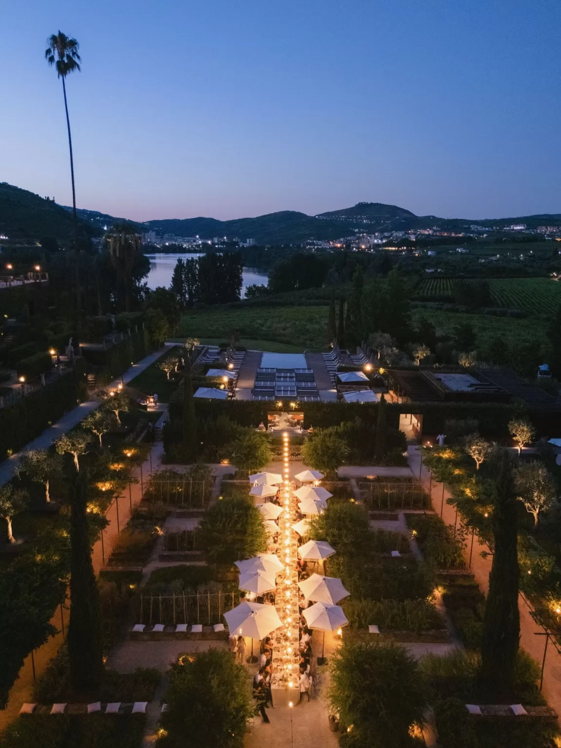 Candlelit wedding dinner under white umbrellas at Six Senses Douro Valley gardens.