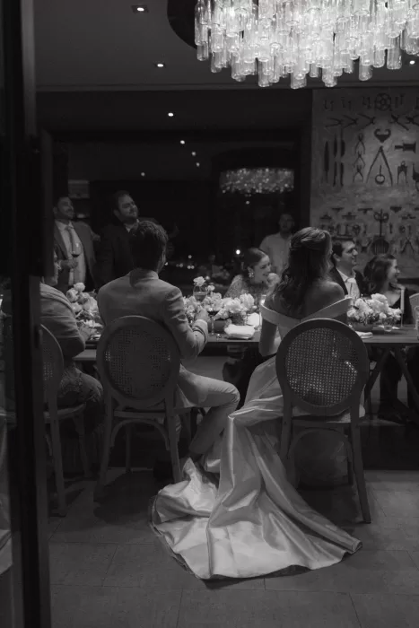 Black and white photo of bride and groom seated at elegant wedding dinner under chandelier at Six Senses Douro Valley.
