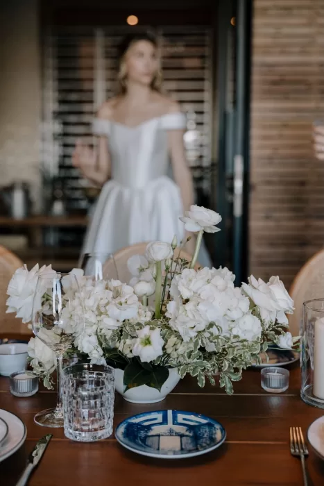 White floral centerpiece with bride blurred in background at Six Senses Douro Valley wedding reception.