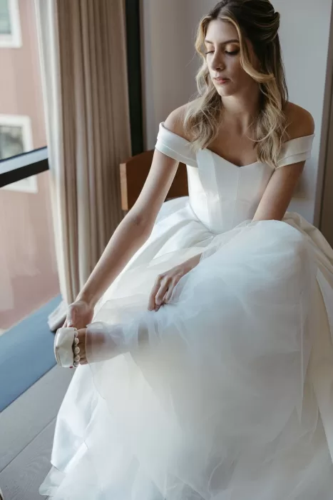 Bride adjusting pearl heels while getting ready by the window at Six Senses Douro Valley.