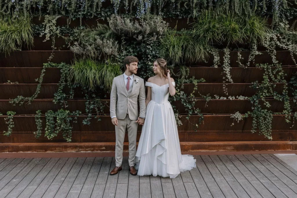 Bride and groom posing in front of lush vertical garden wall at Six Senses Douro Valley.