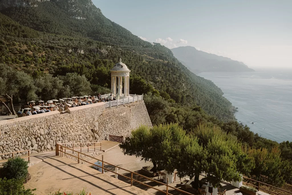 Panoramic view of Son Marroig’s clifftop pavilion overlooking the Mediterranean Sea and Tramuntana mountains during a wedding ceremony.