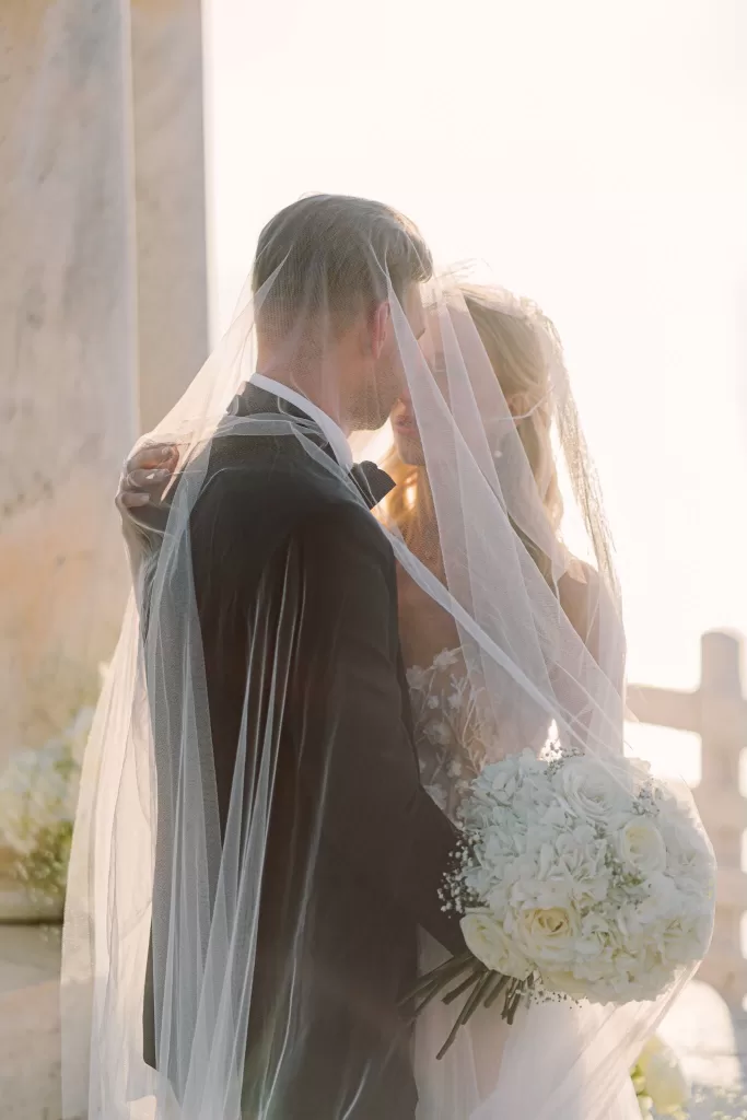 Intimate moment of the bride and groom under the bride’s veil holding a bouquet of white roses at Son Marroig.