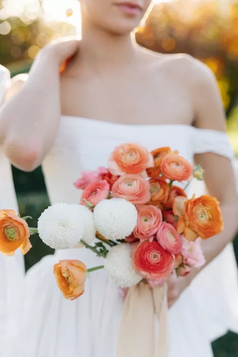 Bride holding a vibrant bouquet of orange and white blooms at Villa Arvedi.